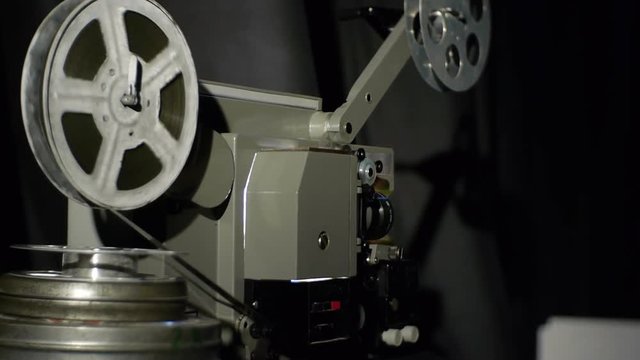Old film projector playing in the night. Close-up of a reel with a film. The film has run out of film