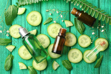 Composition with cucumber essential oils on wooden background, top view