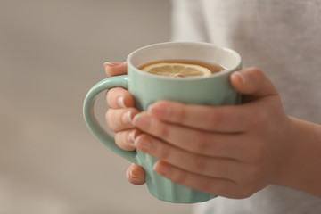 Young woman with cup of hot tea at home, closeup