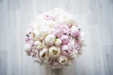 Beautiful bouquet of pink and white peonies in a box on the floor. The view from the top.