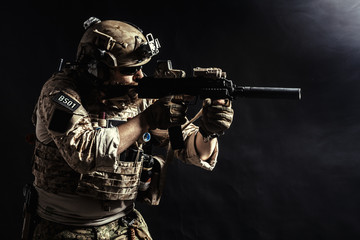 Special forces soldier with rifle on dark background