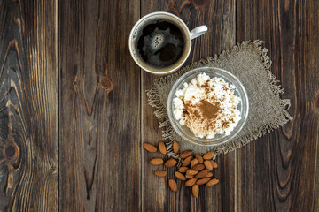 Cottage cheese with sour cream, cinnamon and almond on dark wooden background. Healthy diet food. Protein meal.