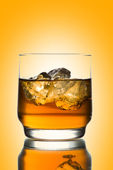 whiskey with ice on yellow background