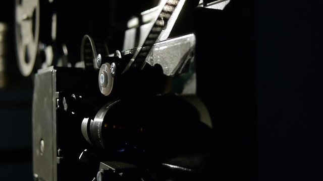 Old film projector playing in the night. Close-up of a reel with a film
