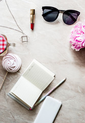 Beauty flat lay with a diary, smartphone, accessories and peonies on a marble background