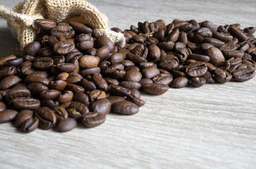 Roasted brown coffee beans  with small sack  on wooden table background