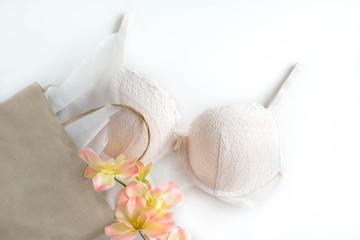 Light pink bra with a paper bag on the white background with flowers