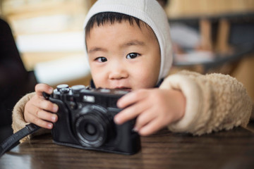 Little boy holding camera on table