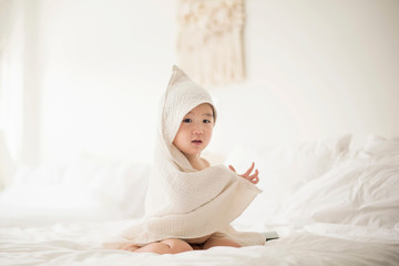Little boy with hooded towel in bed