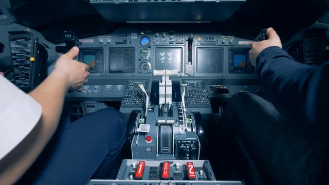 Two men are sitting in a cockpit of a flight simulator and are operating a flight