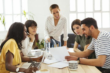 Smiling colleagues working together at desk in office