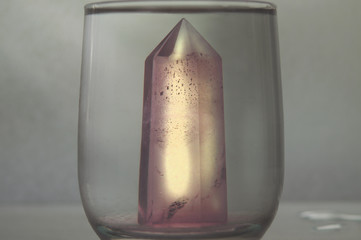 Large mystical faceted quartz crystal in a glass of purified water on an abstract background...