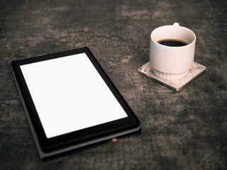 Blank screen tablet mock up on a wooden surface and a cup of coffee on the side