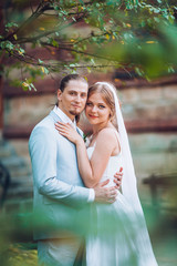 Romantic couple on valentine's day. Man hug a woman in back against the backdrop of a wooden wall of the house. Love story concept. Wedding day of newlyweds bride and groom.