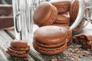 Glass jar and delicious chocolate macarons on table
