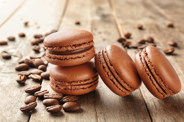 Delicious chocolate macarons and coffee beans on table