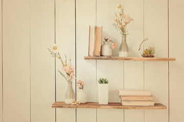 wooden shelves with books and flowers on the wall