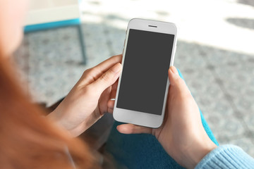 Woman using mobile phone indoors, closeup