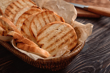 Tasty toasted bread in basket on table, closeup