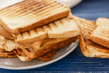 Plate with tasty toasted bread on table