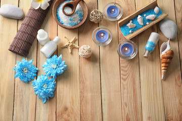 Beautiful spa composition with sea salt, flowers and candles on wooden background, top view