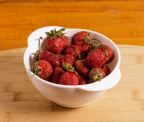 Red strawberries in a deep white plate.