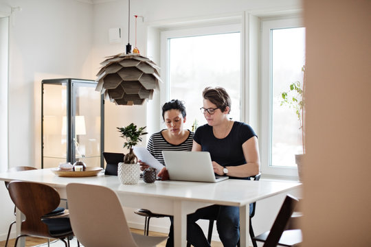 Lesbian couple discussing financial bills over laptop while sitting at table