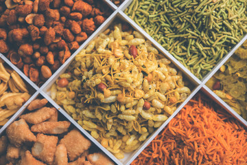 Indian Tea-time snacks like sev, chivda, farsan, mixture, boondi, bakarwadi etc served in white...