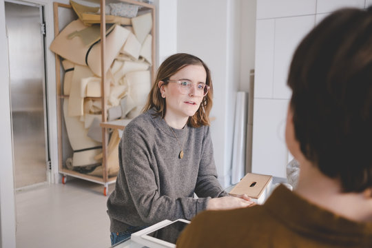 Young female entrepreneur discussing with colleague in upholstery workshop