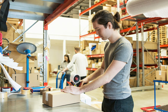 Man Packing Box In Warehouse