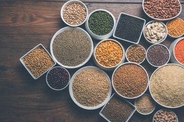 Uncooked pulses,grains and seeds in White bowls over wooden background. selective focus