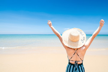 Fototapeta na wymiar woman with straw hat on the beach on a sunny day