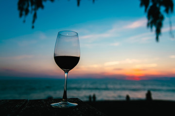 glass with wine at sunset on the table above the sea.
