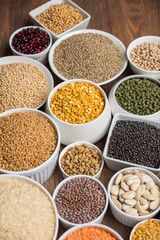 Uncooked pulses,grains and seeds in White bowls over wooden background. selective focus