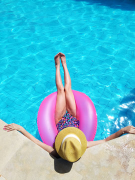 Young beautiful girl relaxing and swimming in the blue swimming pool with a pink circle closeup