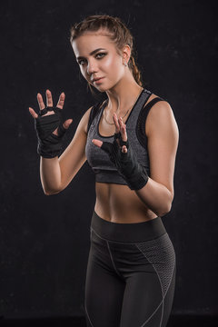  Beautiful sportswoman in boxing bandages on a black background