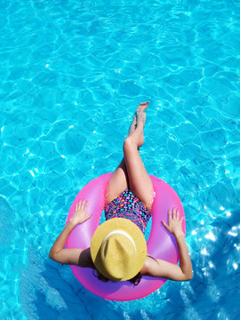 Young beautiful girl relaxing and swimming in the blue swimming pool with a pink circle closeup