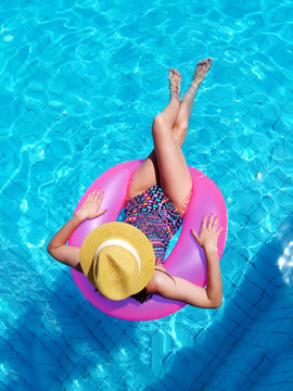 Young beautiful girl relaxing and swimming in the blue swimming pool with a pink circle closeup