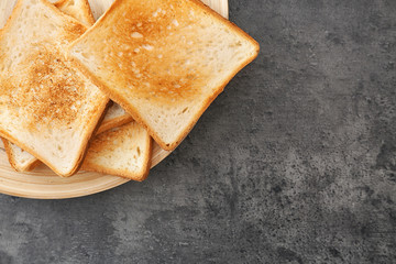 Plate with toasted bread on grey background