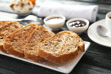 Plate with tasty toasted bread on table