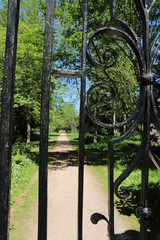 Garden path seen through wrought iron gate in formal garden
