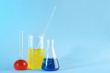 Chemical glassware with colorful samples on color background