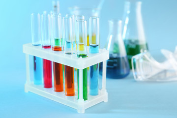 Test tubes with colorful liquids in holder on color background