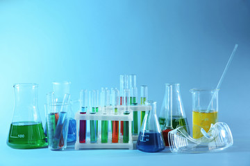 Chemical glassware with colorful samples on color background
