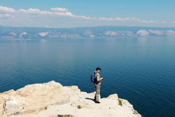 A man-traveler looks at a blue lake. Lake Baikal.