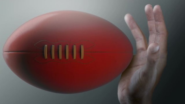A closeup of an aussie rules ball caught in ultra motion flying through the air about to be caught by a dirty hand