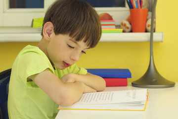 The boy does his homework at his desk at home