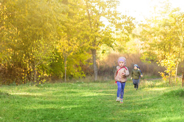 Little blond caucasian girl running in park or forest on bright autumn day. Child having fun playing outdoors. Happy healthy childhood activity and leisure concept