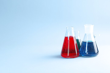 Flasks with colorful liquids on color background