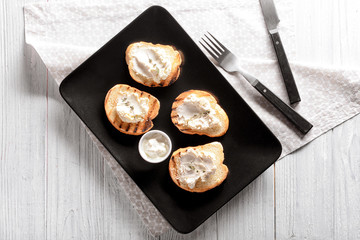 Delicious toasts with cream cheese on plate